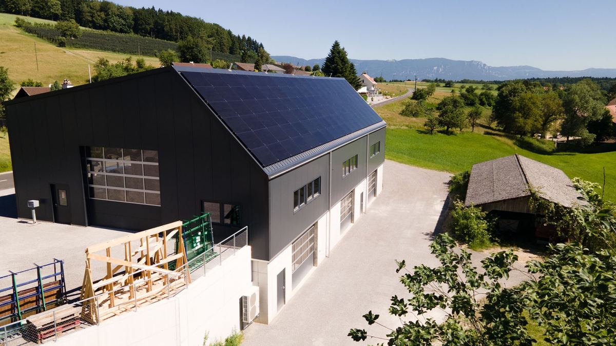 Landwirtschaftliche Halle mit Solaranlage auf dem ganzen Dach, im Hintergrund Wiesen und Wald